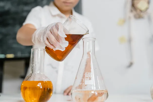 Pouring liquid into a flask in a lab.